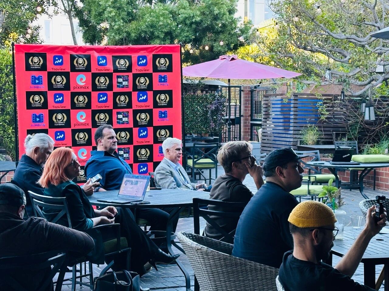 Neu Wave AI Film Festival attendees gathered in front of the event sponsor backdrop